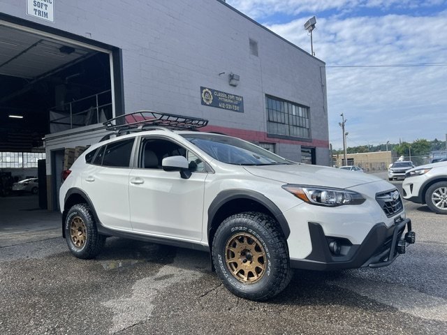 Lifted white SUV with roof rack and bronze wheels
