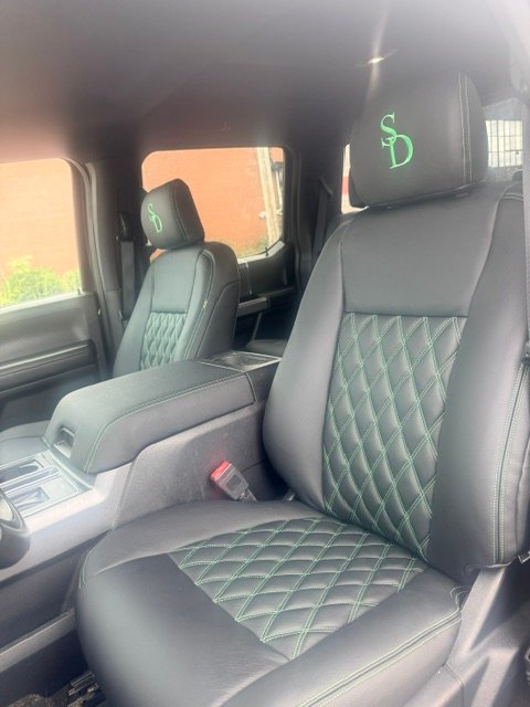 Black leather with green diamond stitching and embroidered initials in a Ford truck