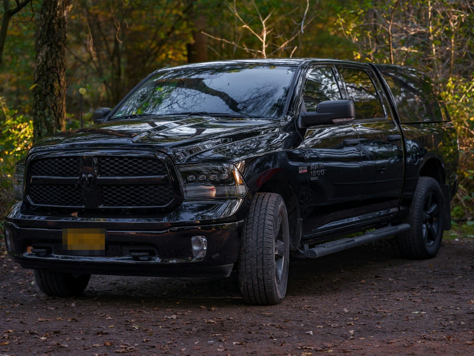 A black Ram 1500 crew cab parked on a wooded trail